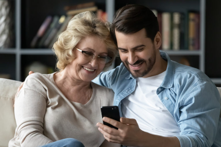 Smiling,Middle-aged,60s,Mother,Rest,With,Grown-up,Son,Using,Smartphone