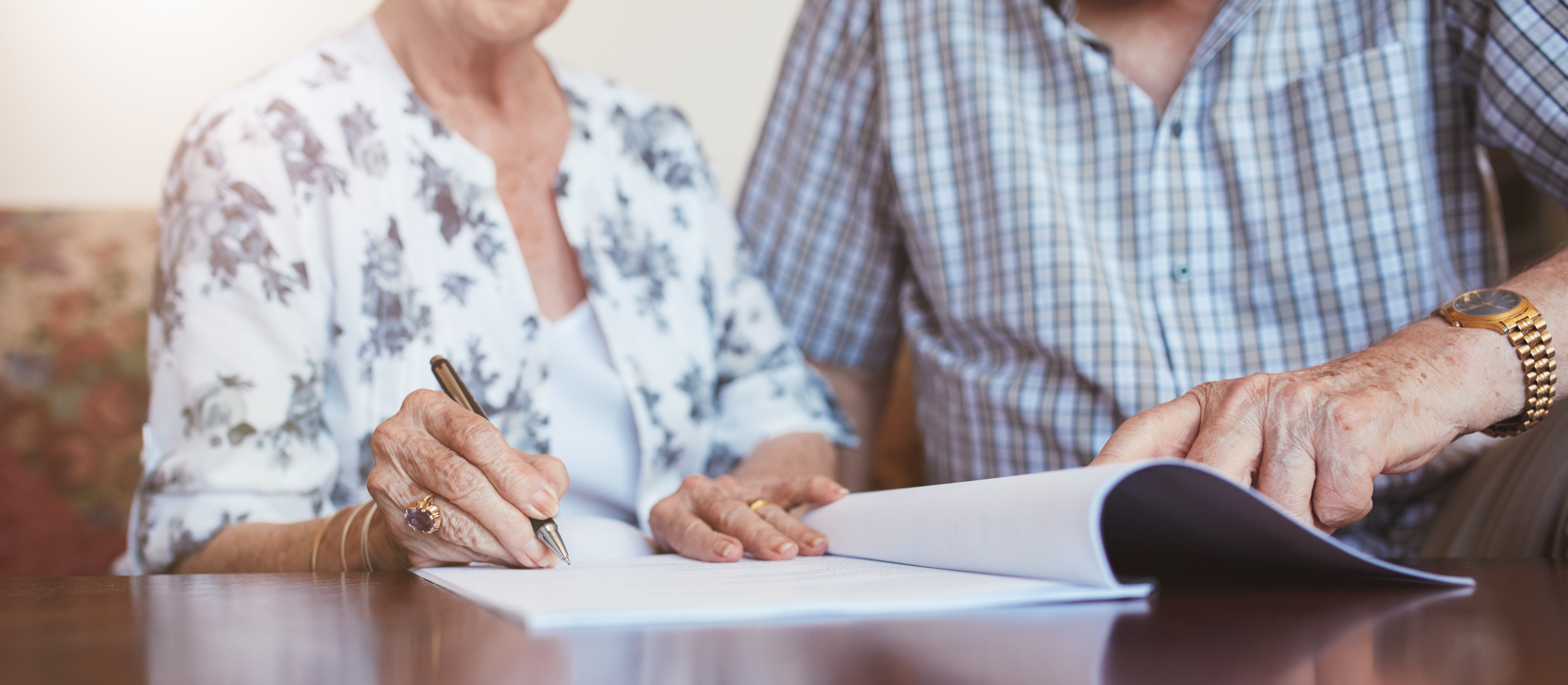 Senior woman signing documents with her husband