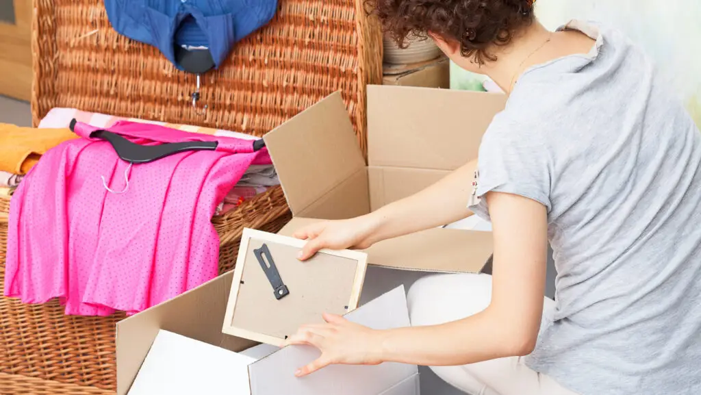 A woman packing picture frames into a cardboard box