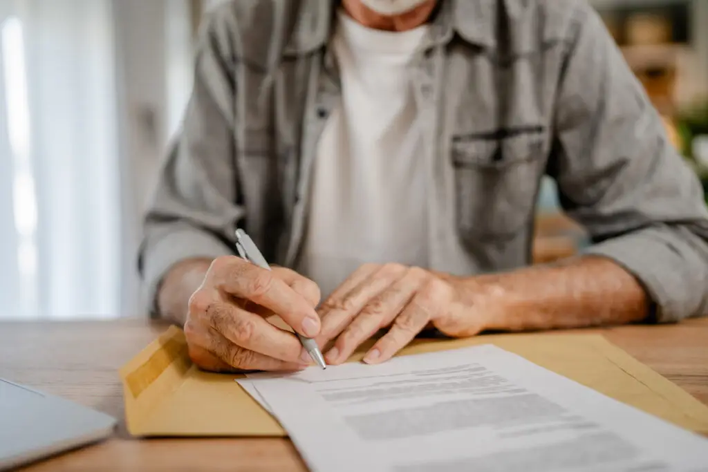 senior caucasian man open mail letter sign contract document at home