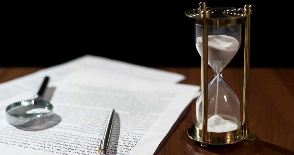 Close-up of document and hourglass on table, contract validity period expiring