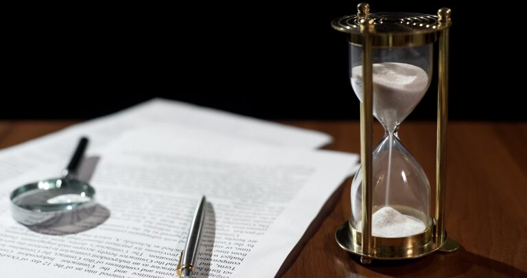 Close-up of document and hourglass on table, contract validity period expiring