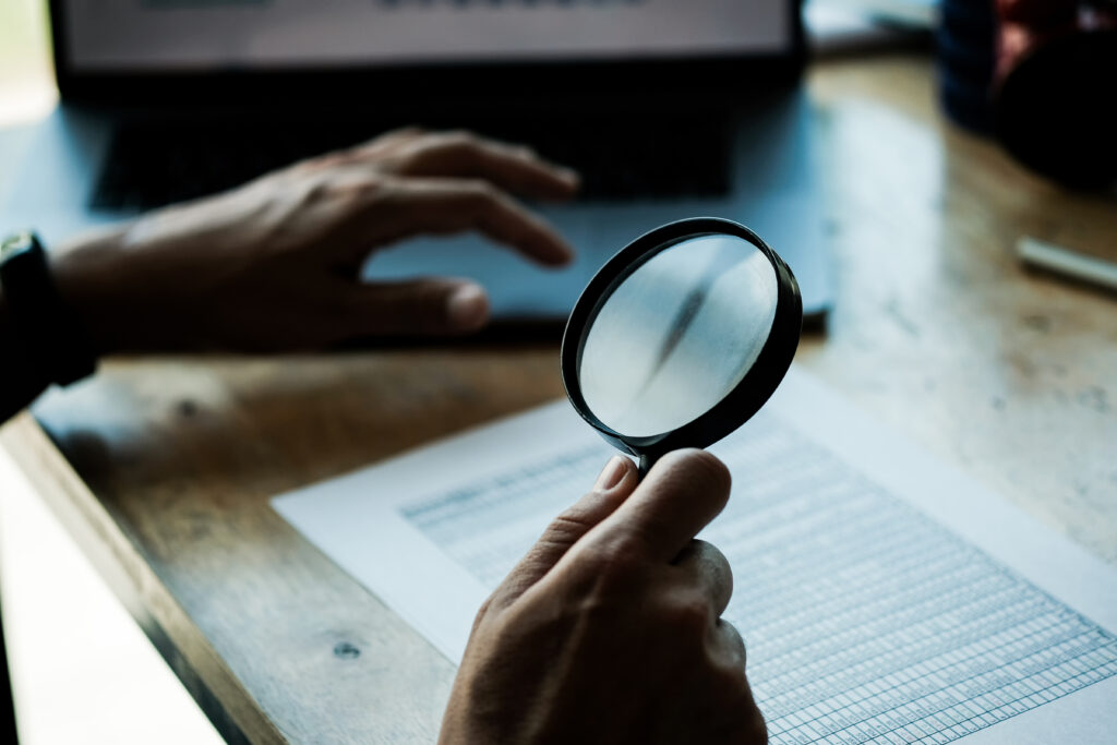 Businessman looking through a magnifying glass to documents