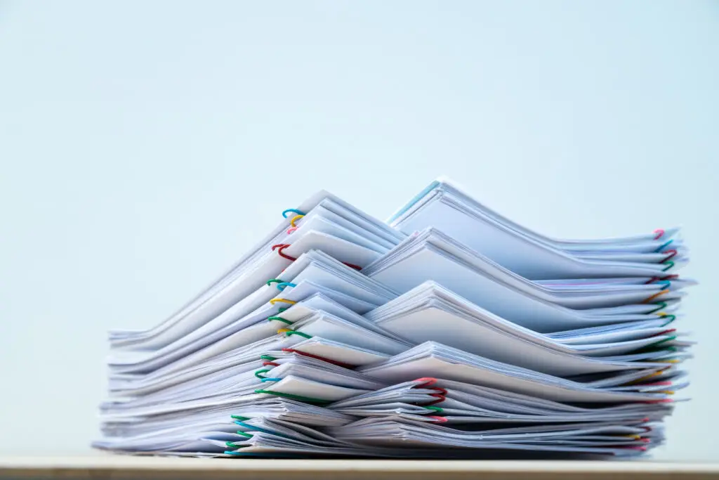 Stack of document paper with colorful paperclip place on wooden table with copy space