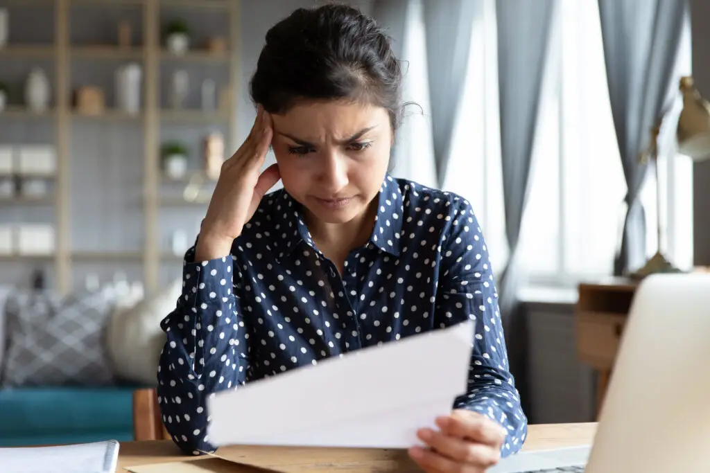 Indian ethnicity woman sit at desk reading letter feels disappointed