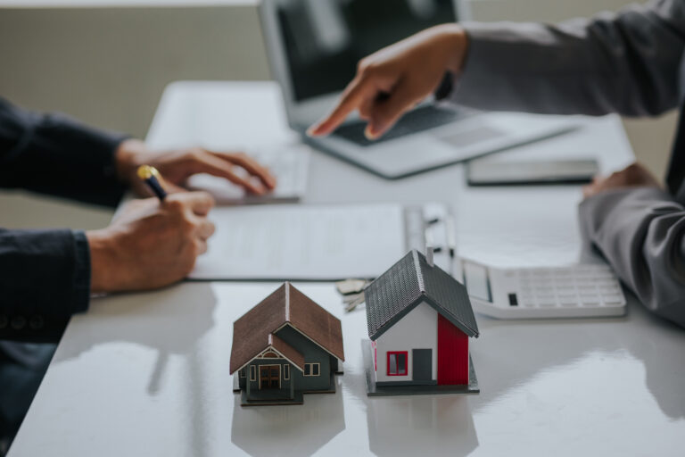 Businessman or real estate agent with house model laying down contract, having contract in place to protect it, signing little agreement form in office, keeping real estate, moving house or renting pr